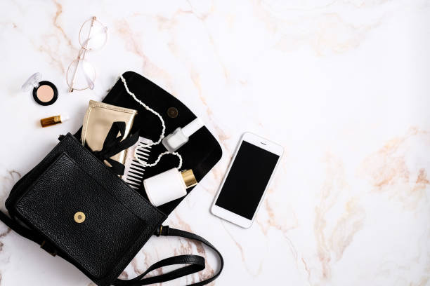 istock Black leather women's handbag with accessories and cosmetics on marble table. Flat lay, top view. 1365562716