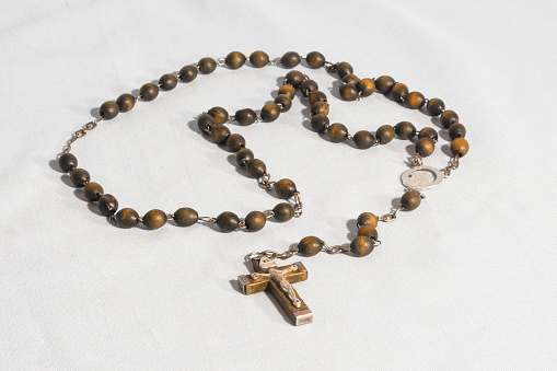 Catholic wooden rosary for prayer on a white background.