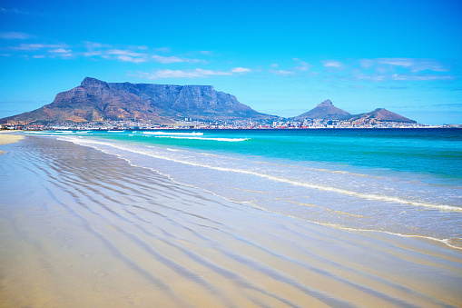 Beautiful view of Cape Town and its famous Table Mountain from a deserted beach at Milnerton, with plenty of copy space in the sky and beach sand.