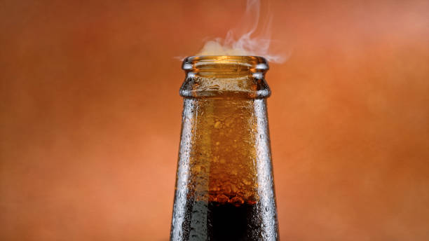 Mouth of a brown glass bottle Close-up of vapour coming form the mouth of a brown glass bottle against brown background. BOTTLE OF BEER stock pictures, royalty-free photos & images