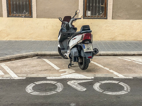 Valencia, Spain - September 19, 2021: Lonely motor scooter parked in dedicated space.  Their use became so extensive that the city government provides places to park them in the street