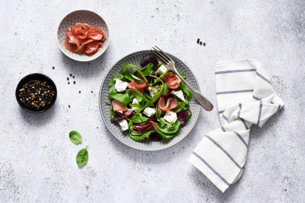 Arugula salad, chard with blue cheese and prosciutto with sauce on a concrete background, top view. stock photo