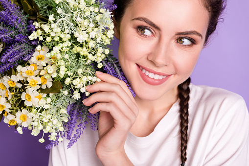 Cropped photo of young cheerful girl happy positive smile look wild flowers spring isolated over violet color background.