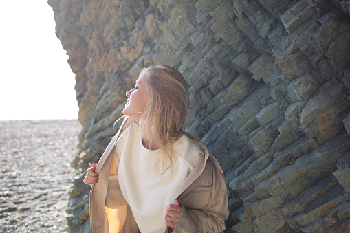 portrait of a young beautiful woman on the seashore against the background of rocks