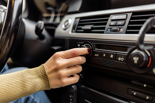 Woman turning button of radio in car