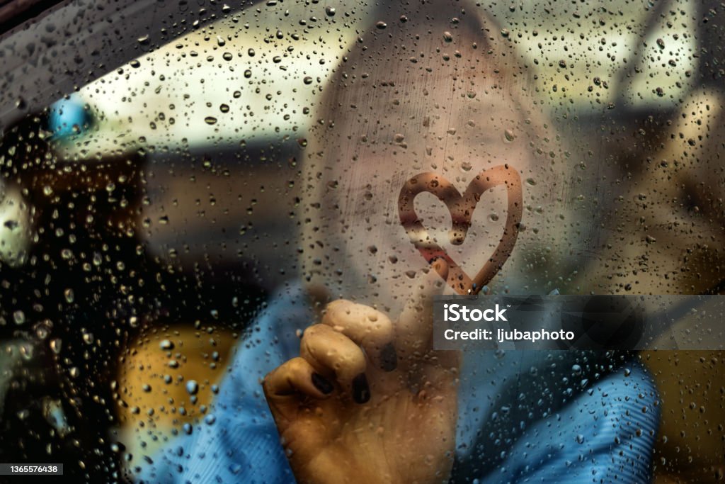 Heart shape on car windshield Happy woman drawing heart on car window during rainy day Car Stock Photo