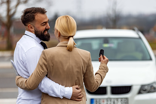 Young man and woman in a car rental service standing hugging