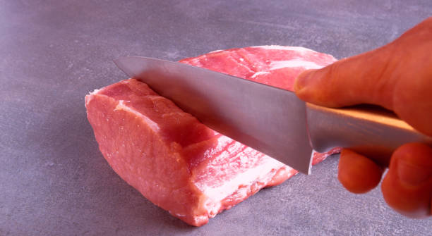 istock The chef is cutting fresh raw meat into steaks. Close-up on a gray background. 1365580448