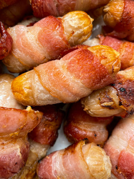 istock Full frame image of pigs in blankets (pork cocktail sausages wrapped in bacon) on white plate, elevated view 1365580533