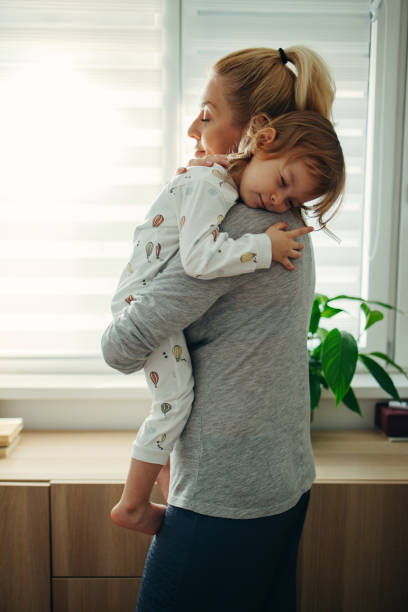 tiempo de sueño: madre sosteniendo a su hija adormecida por la mañana - playing playful baby contemporary fotografías e imágenes de stock