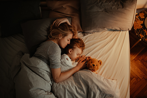 Madre e hija amorosas durmiendo juntas en la cama por la noche photo