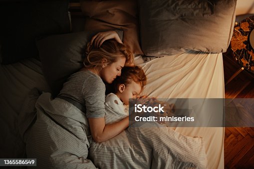 istock Loving Mother and Daughter Sleeping Together in Bed in the Evening 1365586549