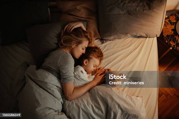 Loving Mother And Daughter Sleeping Together In Bed In The Evening Stock Photo - Download Image Now