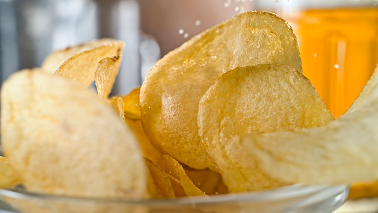 Close-up of slated potato chips in glass bowl on table.
