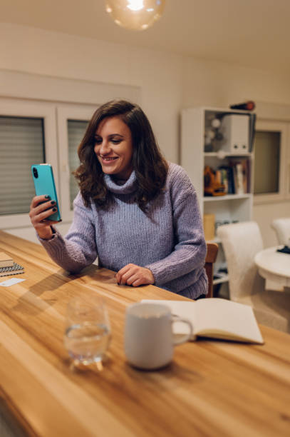 istock Hispanic woman is using smartphone for a video call while at home 1365590319