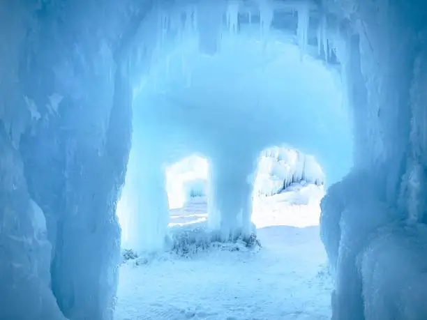 Horizontal blue frozen icy tunnel. Dangling icicles