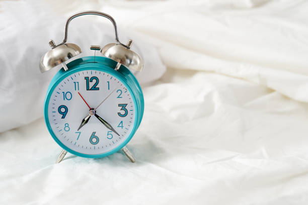 istock Alarm clock in the bed at home. Morning time background concept with copy space 1365595689