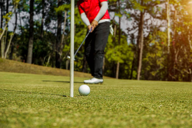 golfista che mette la pallina da golf sul campo da golf il bagliore dell'obiettivo al crepuscolo al tramonto. - golf swing golf golf club golf ball foto e immagini stock