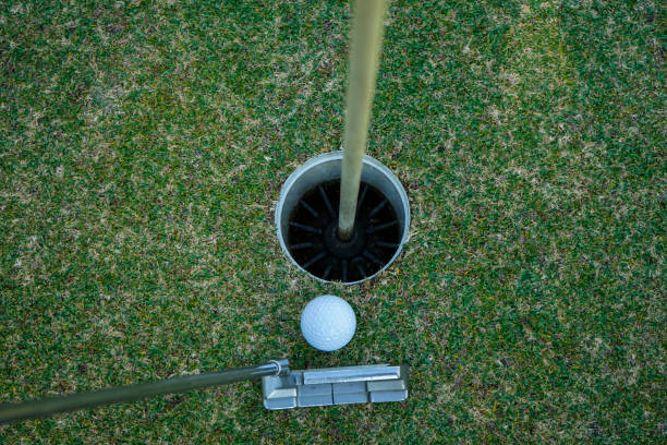 グリーン上にゴルフボールを置くゴルファーの練習トレーニング、夕方�の太陽の上にレンズフレア - golf green practicing sports training ストックフォトと画像