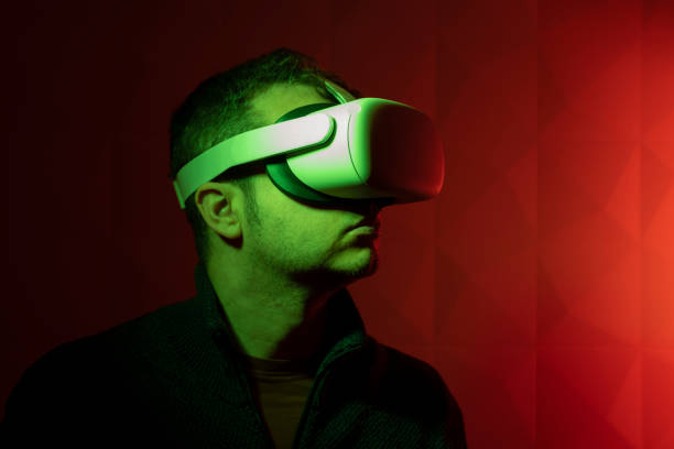 istock Man with white virtual reality goggles with red background and side green light 1365598250