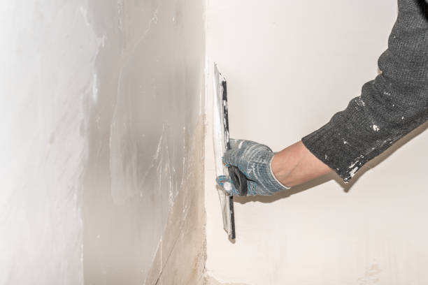 istock The hands of a worker level the walls with a spatula using putty during repairs. 1365598511
