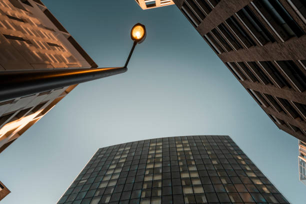 A view from below of the street lamp illuminating between the office buildings.