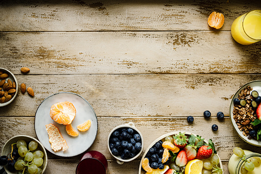 Top view of a healthy breakfast on wooden table with copy space. Fresh fruits salad with chocolate granola and orange juice.