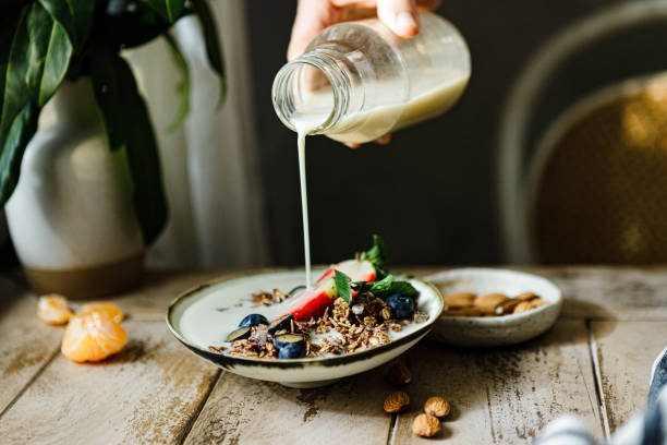 наливание молока в шоколадную гранолу с фруктовой миской - milk breakfast berry fruit granola стоковые фото и изображения