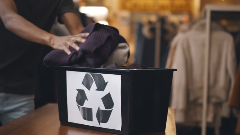 Charity shop workers packing clothes in plastic container for recycling