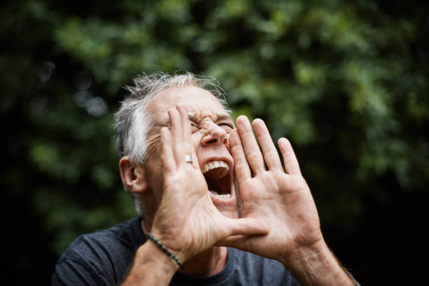 Hear this! Mature man cups his hands and shouts, mouth wide open stock photo