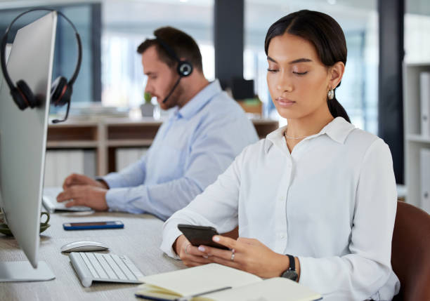 istock Shot of a young woman using a smartphone in a modern call centre 1365601627