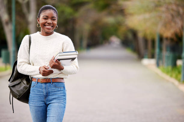 foto de una mujer joven cargando sus libros escolares afuera en la universidad - estudiante fotografías e imágenes de stock