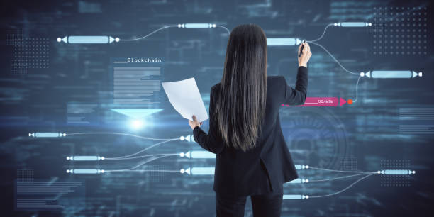 istock Back view of attractive young caucasian businesswoman using abstract glowing big data blockchain interface on dark background. Cryptocurrency, finance, big data and information concept. Double exposure. 1365601829