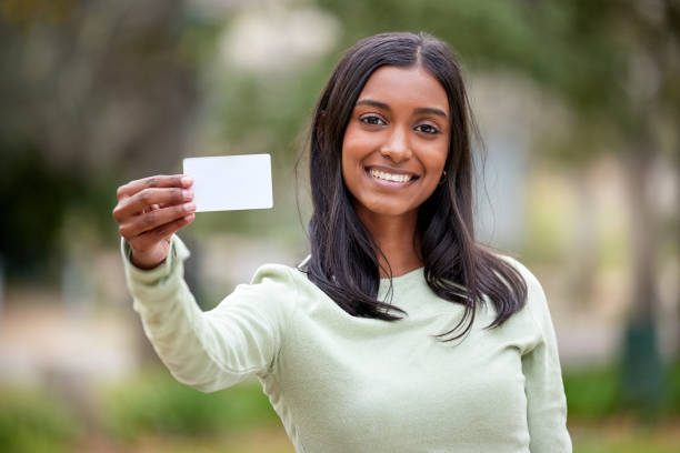 aufnahme einer jungen frau mit einer leeren karte draußen am college - id card identity showing women stock-fotos und bilder