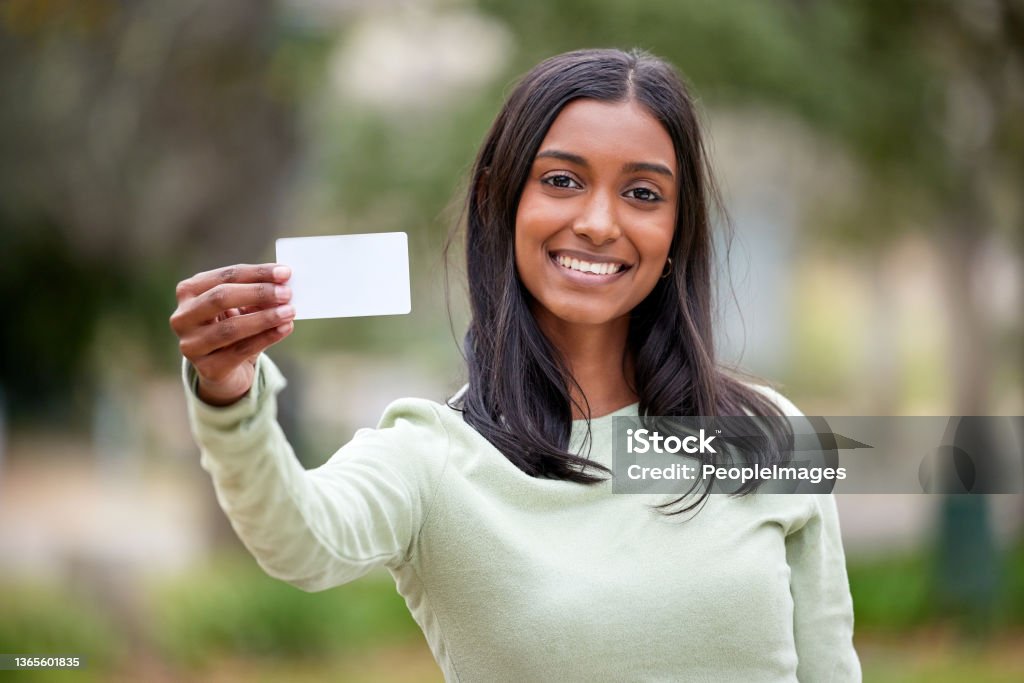 Shot of a young woman holding a blank card outside at college Life doesn't come with a free pass but there's always student cards Holding Stock Photo