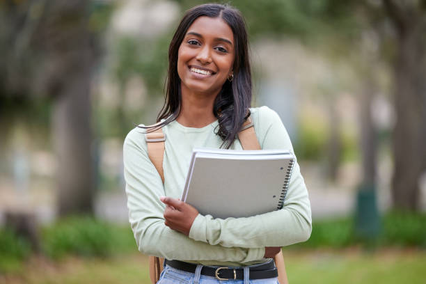 ritratto di una giovane donna che porta i suoi libri di scuola fuori al college - studente universitario foto e immagini stock