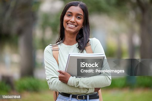 istock Portrait of a young woman carrying her schoolbooks outside at college 1365601848