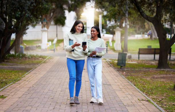 Shot of two young women using a smartphone while studying together at college On the way to a whole new world education student mobile phone university stock pictures, royalty-free photos & images