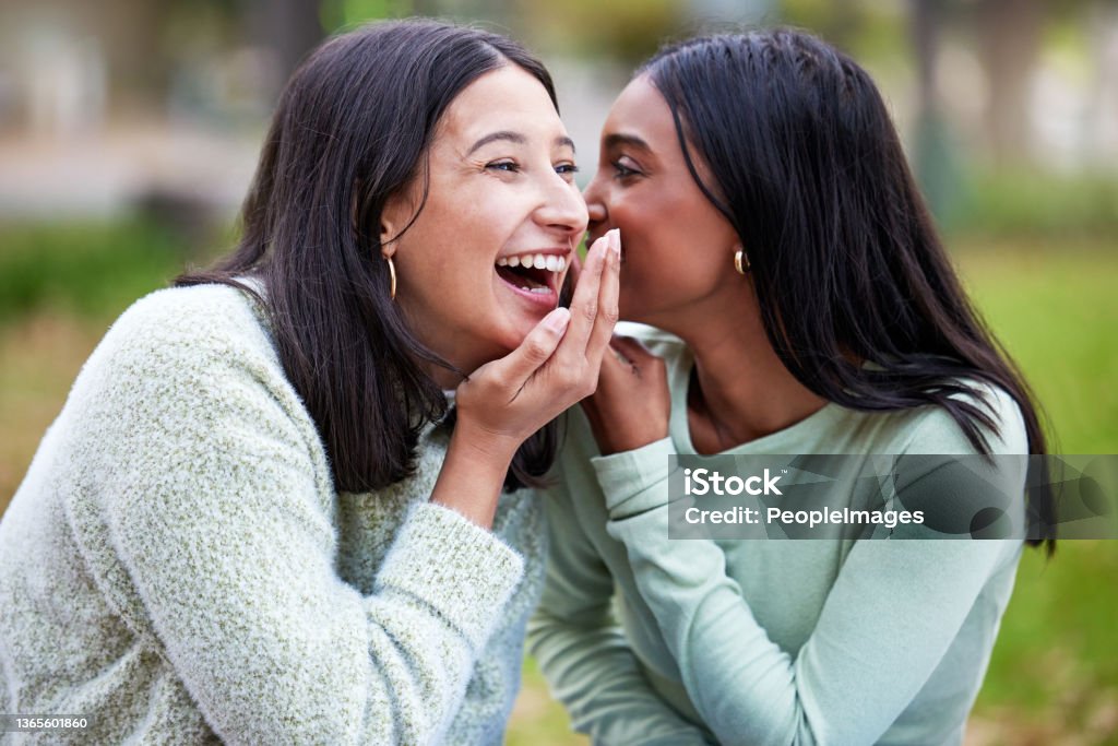 Shot of two young women telling secrets outside at college Nobody brings the funny like a study buddy Gossip Stock Photo