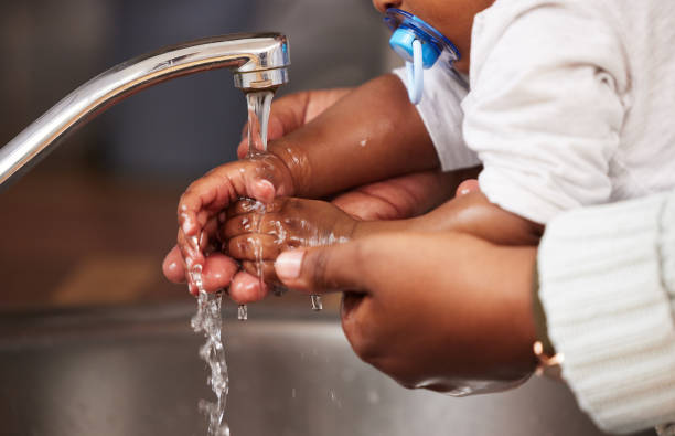 tiro de uma mulher irreconhecível lavando as mãos de seu bebê na pia em casa - bathroom black faucet - fotografias e filmes do acervo