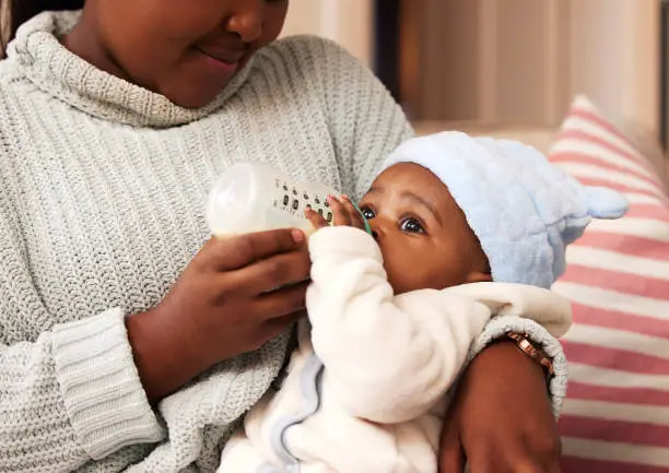 Photo of Shot of an adorable baby girl being bottle fed by her mother at home