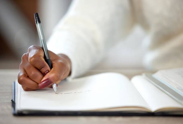 istock Shot of an unrecognisable woman making notes in a book while studying at home 1365602257