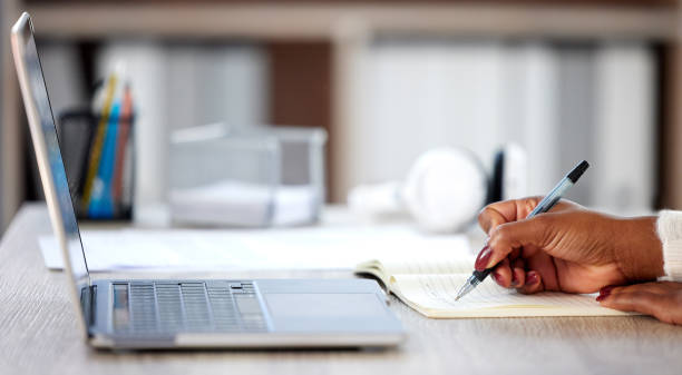 istock Shot of an unrecognisable woman making notes in a book while studying at home 1365602261