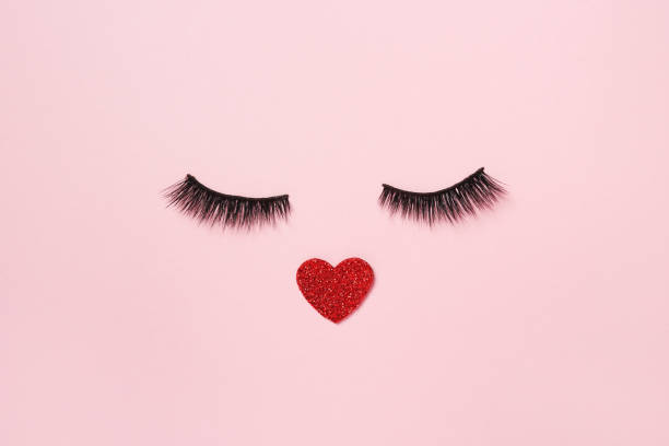 istock Creative photo of heart with false eye lashes on pink background 1365602869