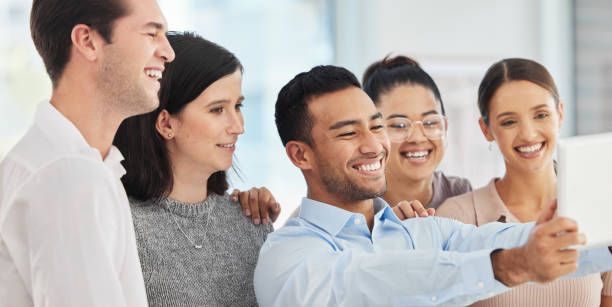 istock Shot of a group of business people taking a selfie using a digital tablet 1365603621