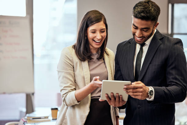 Shot of two young businesspeople using a digital tablet at work