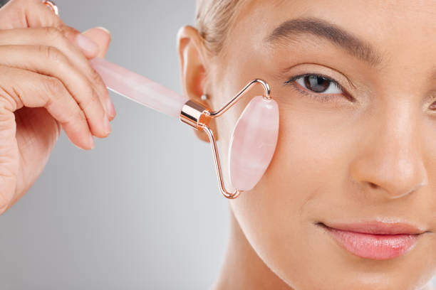 istock Shot of an attractive young woman using a jade roller on her face against a studio background 1365604640