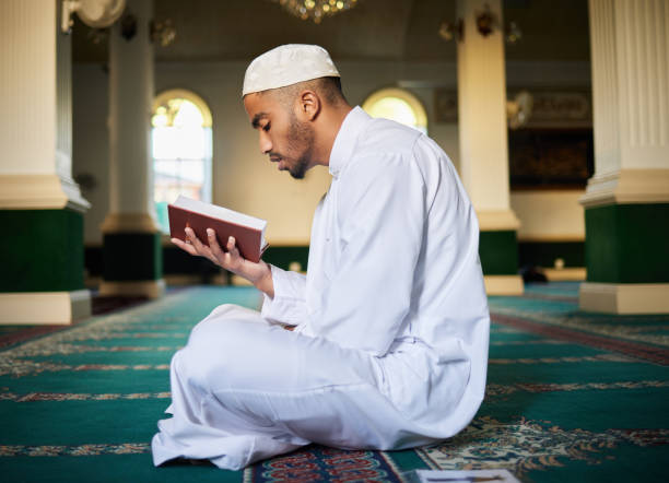 istock Shot of a young muslim male reading scripture in a mosque 1365604741