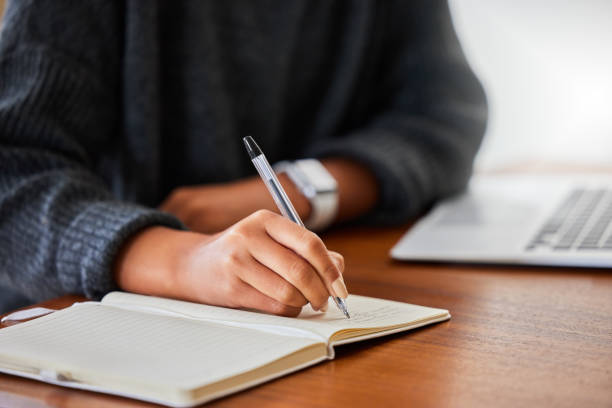 istock Cropped shot of an unrecognizable female entrepreneur writing in her notebook while working at home 1365606029