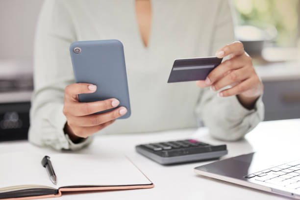istock High angle shot of an unrecognizable businesswoman using her cellphone while holding a credit card in the office 1365606051